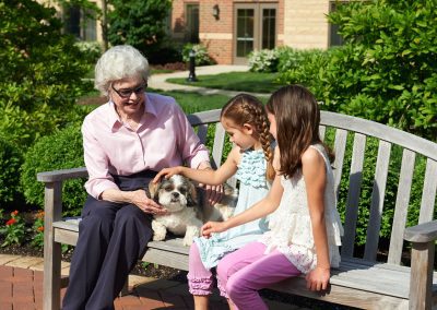 Female resident spending quality time outdoors with her granddaughters at Park Place of Elmhurst