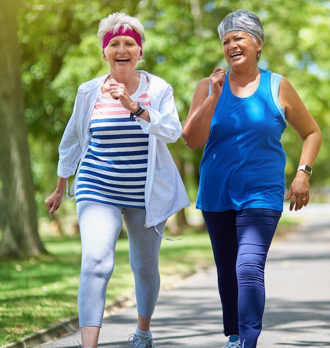 Two senior women fast-walking on a path outdoors
