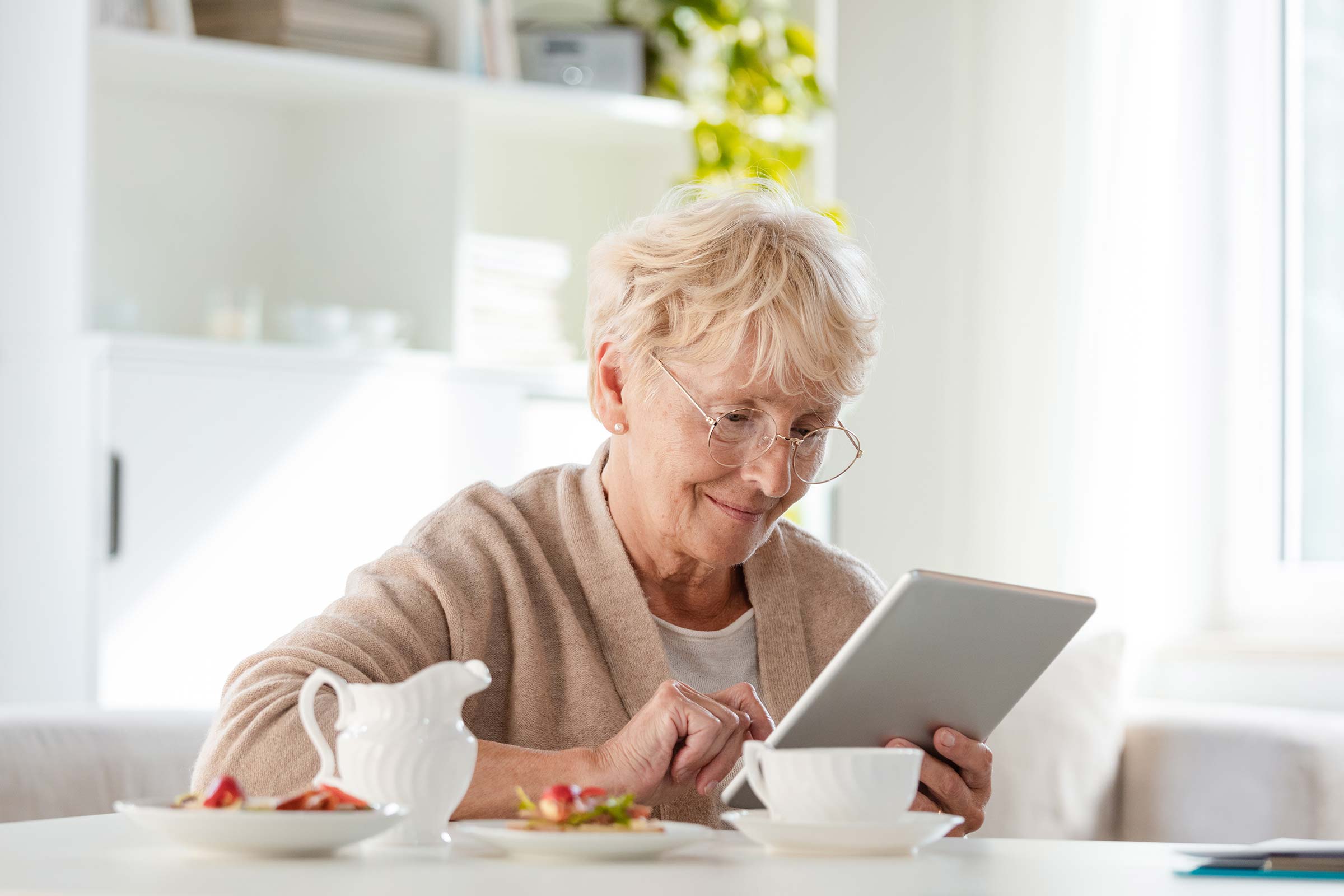Senior woman eating breakfast and using a tablet to research Park Place of Elmhurst