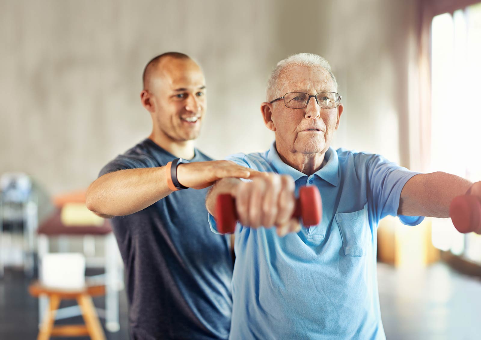 Senior man working with a physical therapist using dumbells